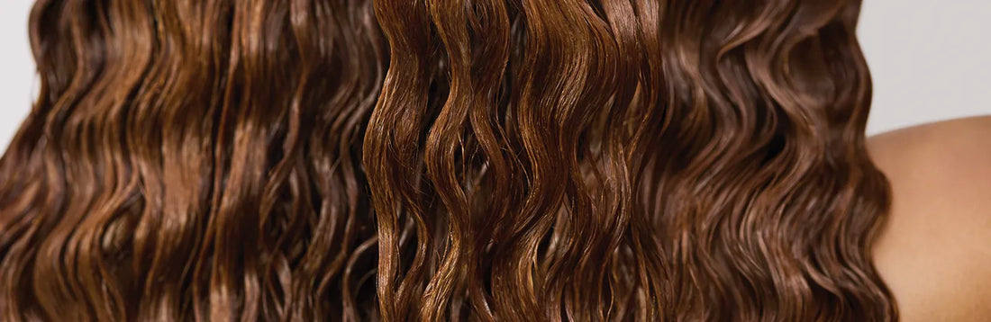 close up image of a woman with long, curly, brunette hair