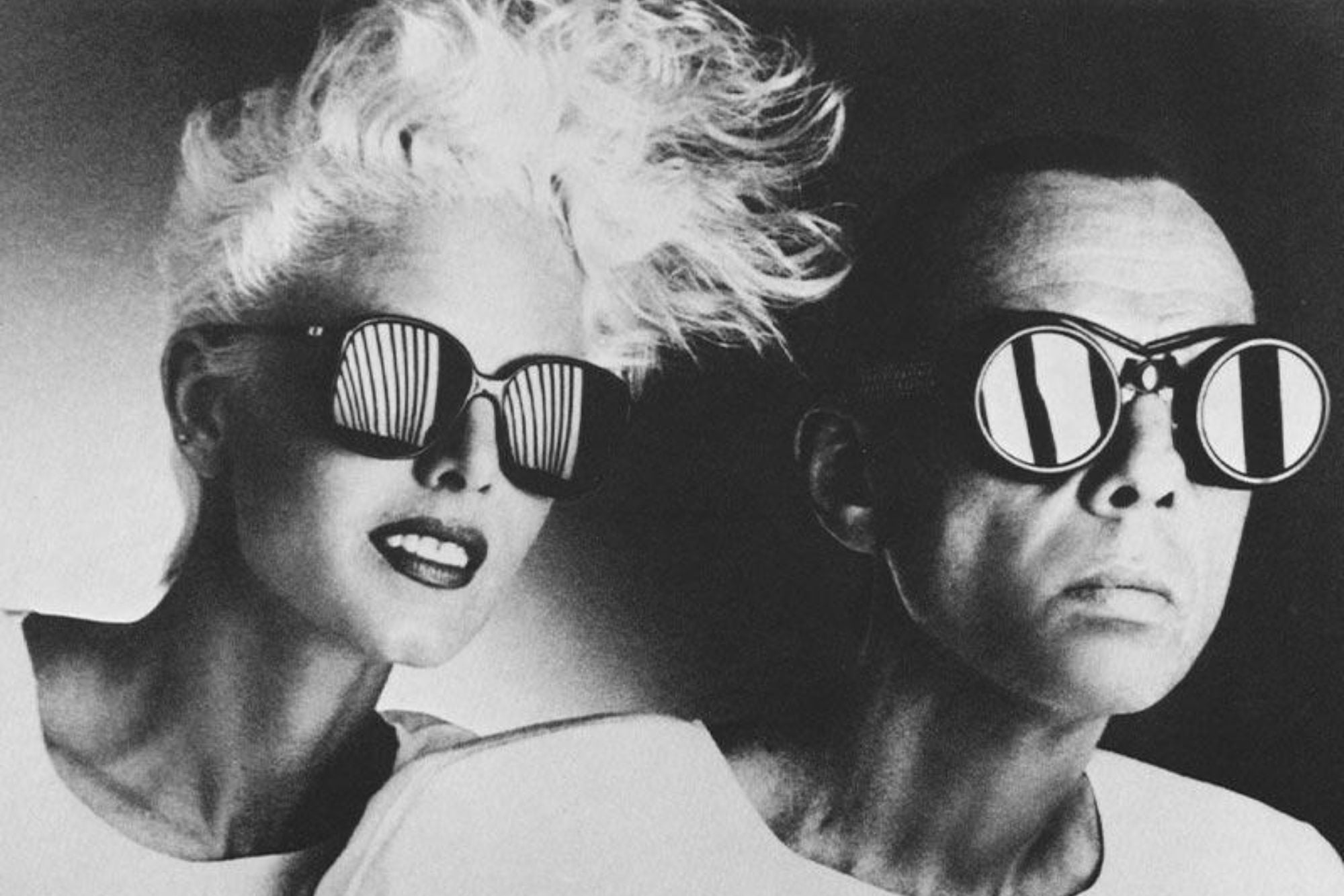 Two people wearing sunglasses in a black and white photo.