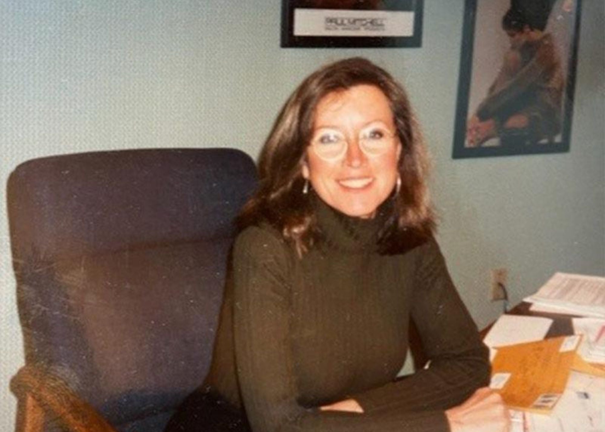 Woman sitting in a chair in an office setting with posters on the wall.