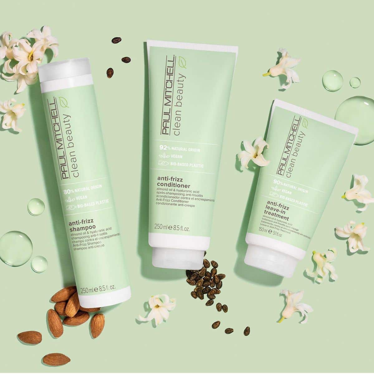 Artistic image of Clean Beauty Anti-Frizz Collection with ingredients surrounding the bottles on a soft green background