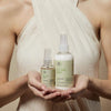 Tea Tree Hemp model holding Tea Tree Hemp Replenishing Oil + Multitasking Spray in front of chest