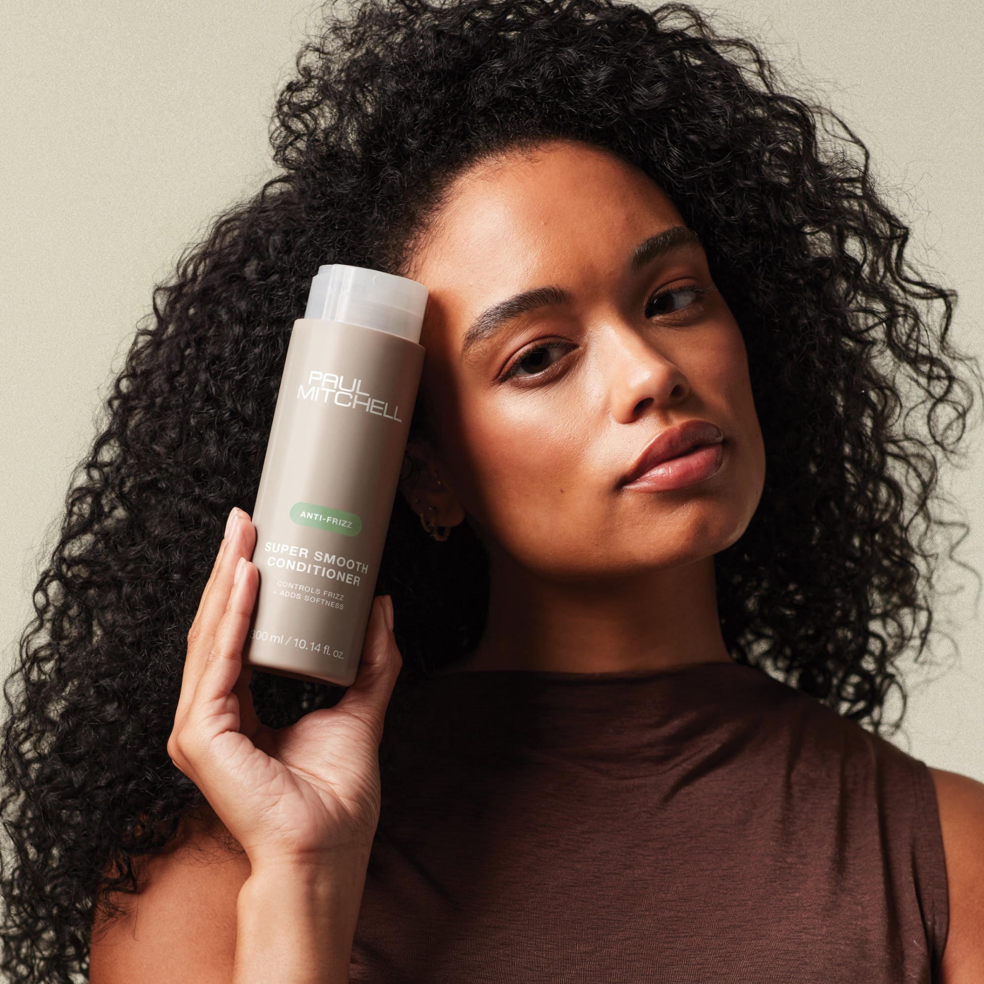 Curly haired model holding Super Smooth Conditioner