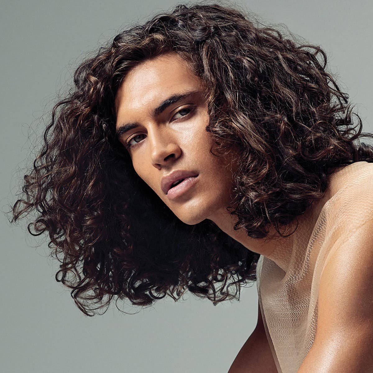 Male model with long curly hair on a neutral background