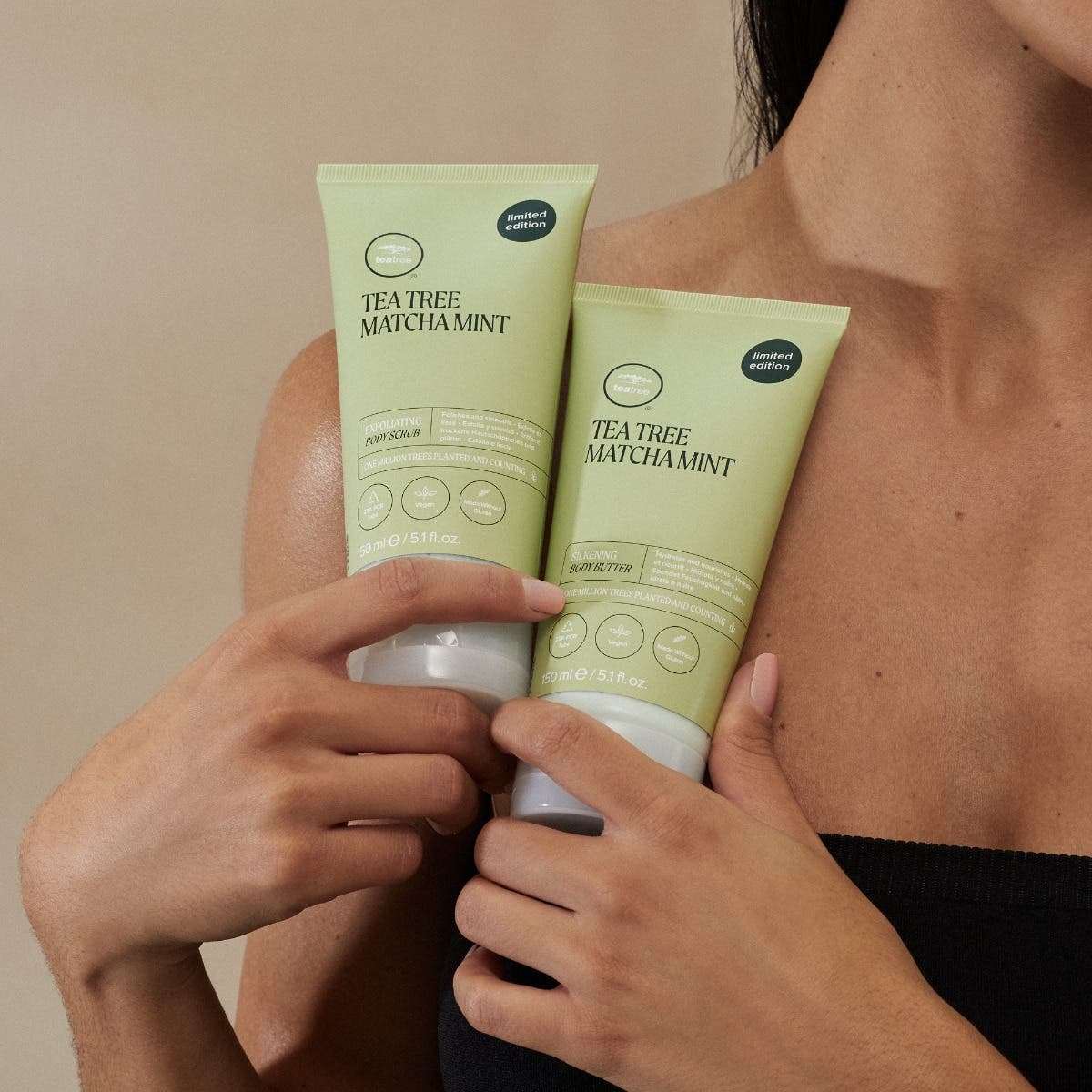 Woman holding Tea Tree Matcha Mint Body Care Duo up against her shoulder / chest
