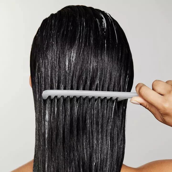 Image of Awapuhi Wild Ginger model using Detangler Comb to evenly distribute Cream Rinse through her hair