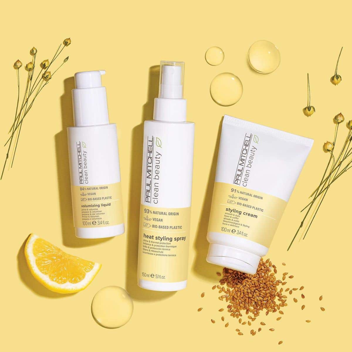 Artistic image of Clean Beauty Heat Styling Collection with ingredients surrounding the bottles on a yellow background.