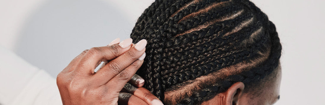 close-up image of a stylist braiding a woman's hair