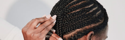 close-up image of a stylist braiding a woman's hair