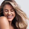 Woman with blonde hair smiling against a neutral background