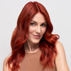 Woman with vibrant red hair against a plain background