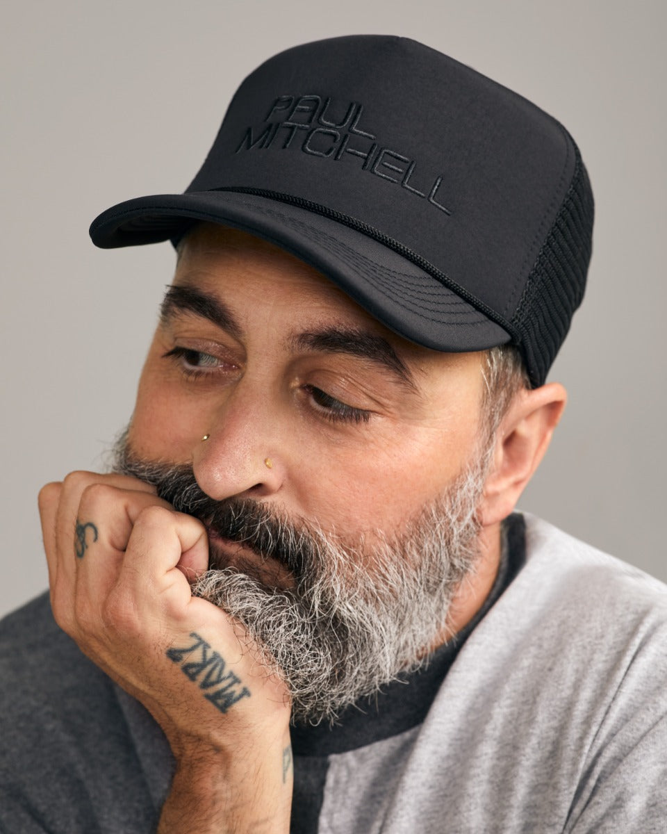 image of a man wearing the Paul Mitchell Trucker Hat; he looks like he's got a lot on his mind